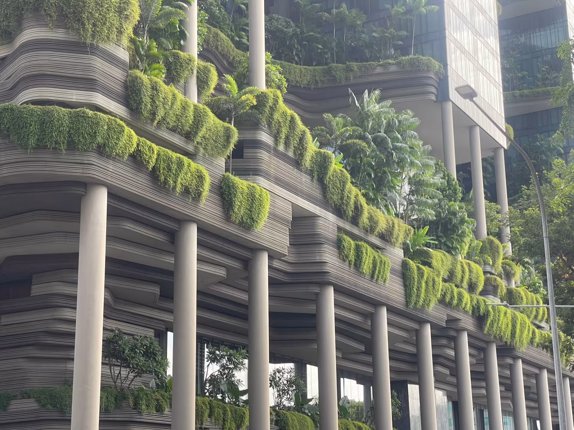 Façade d’immeuble contemporain intégrant une végétation abondante et des terrasses végétalisées dans une architecture urbaine durable.