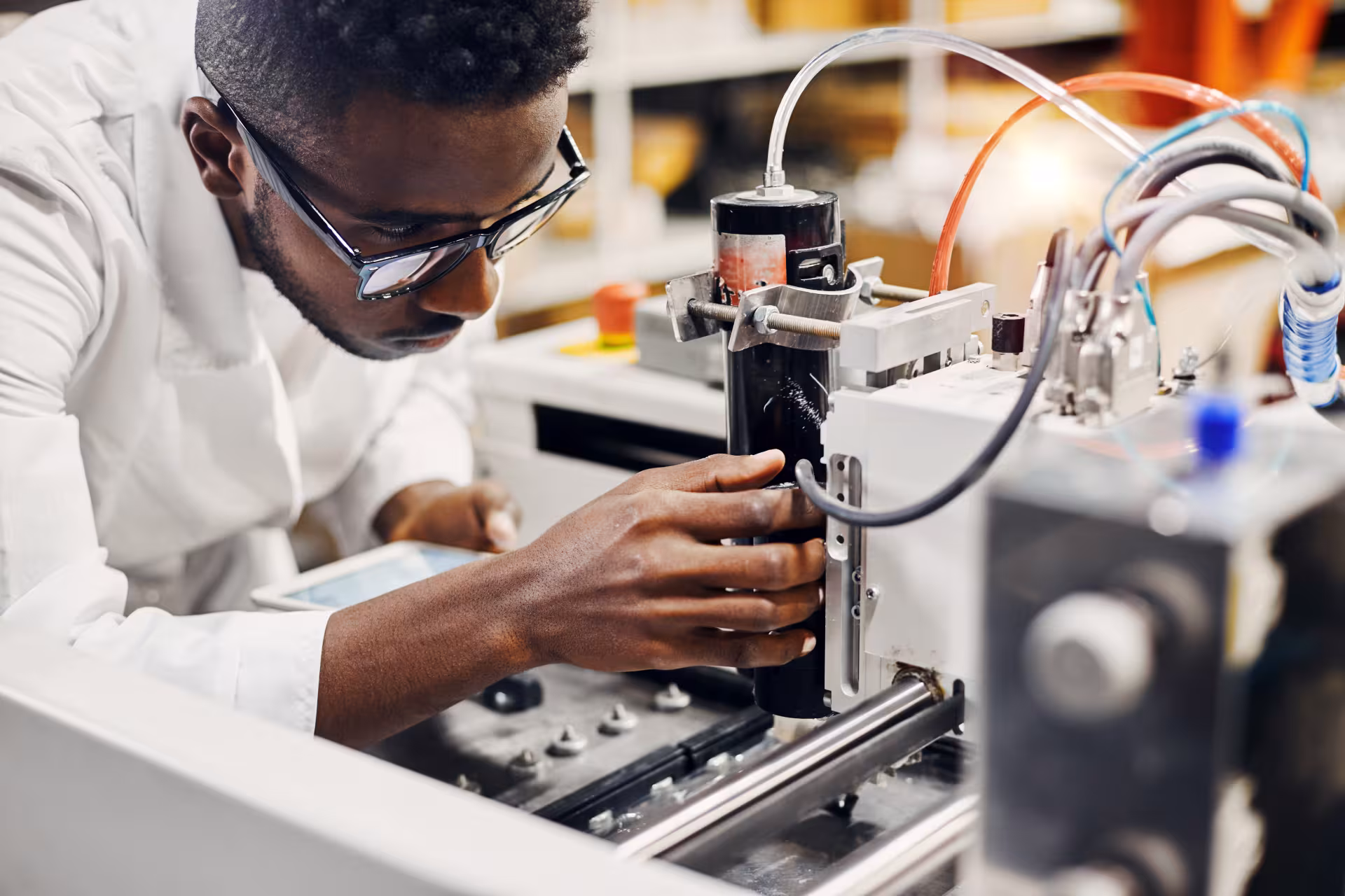 Technicien réalisant des réglages sur un équipement de laboratoire ou de prototypage technologique.