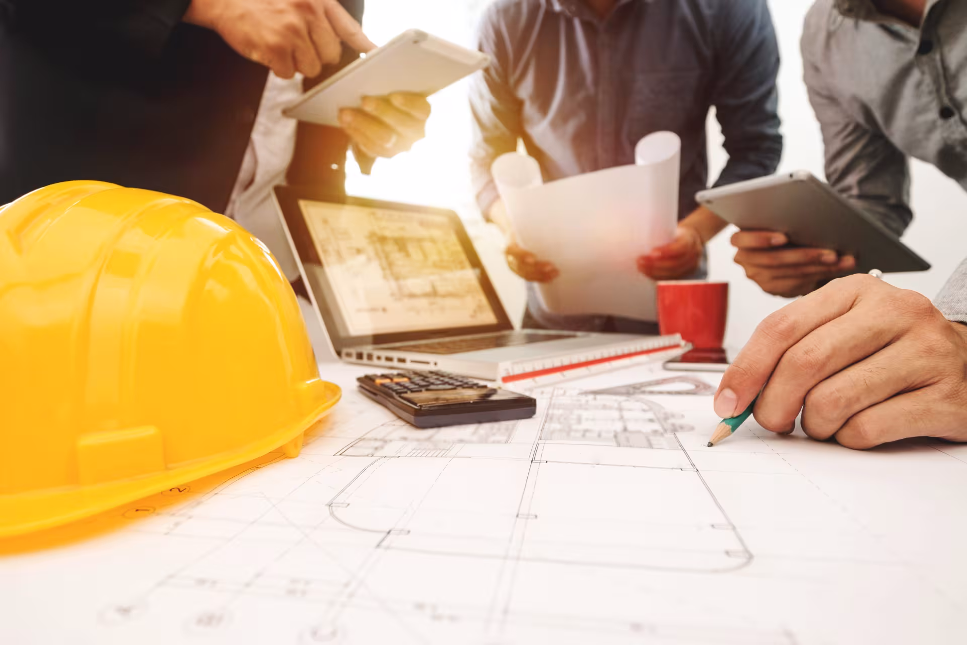 Équipe de professionnels du BTP réunie autour de plans et d’outils numériques pour concevoir et piloter un projet de construction.